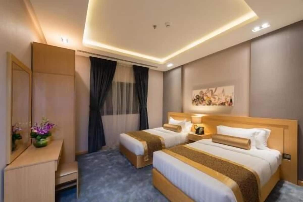 A hotel room with two beds, a desk, a mirror, and a painting on the wall.