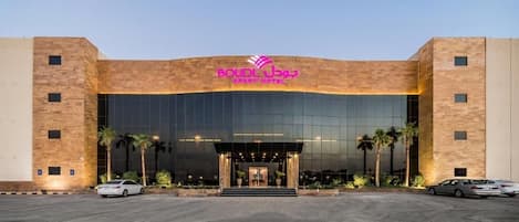 A hotel with a modern facade, a prominent entrance, and a parking area.