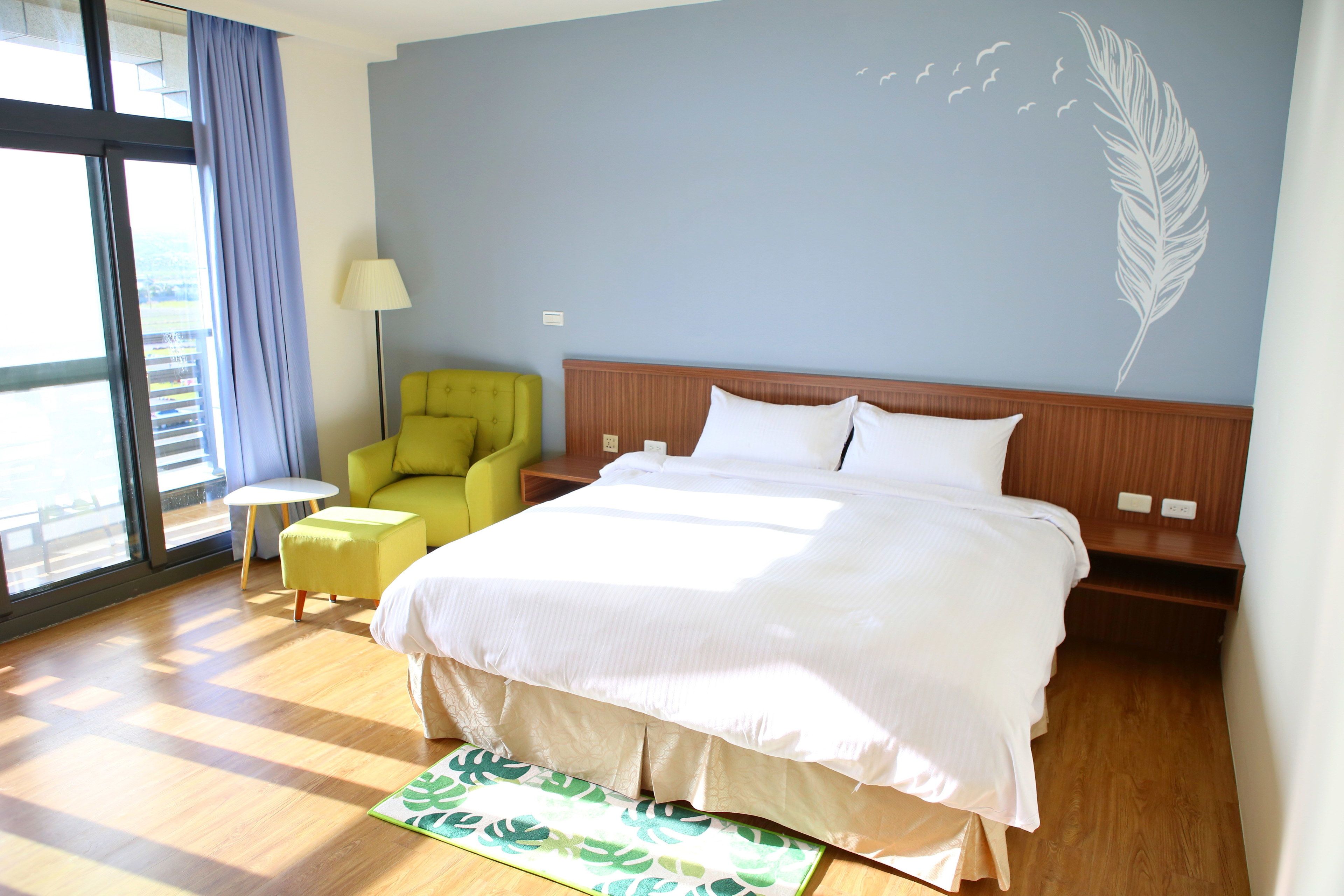Una habitación de hotel con una cama grande, una mesita, una silla y vistas al exterior.