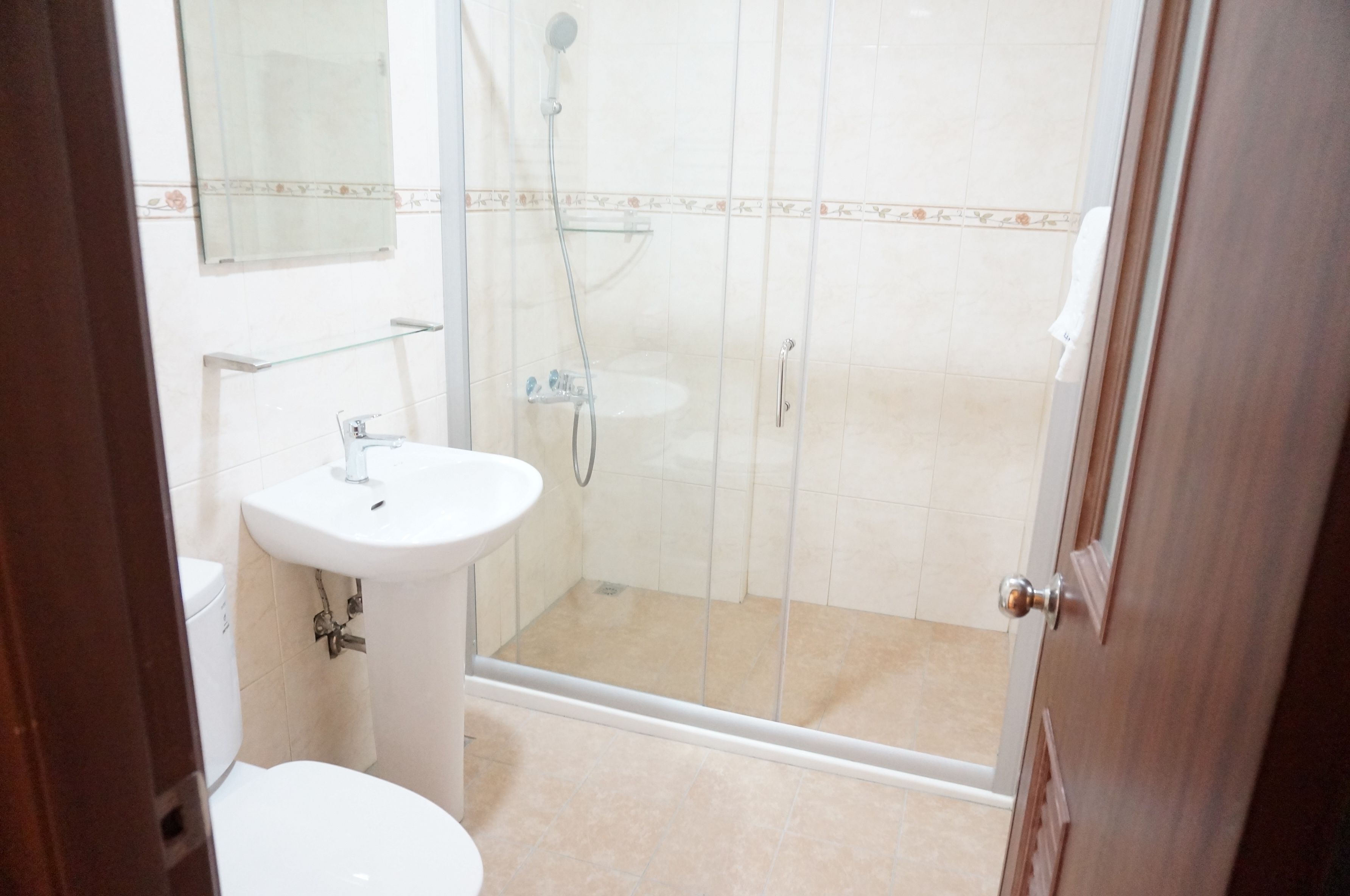 Un baño con inodoro, lavabo y zona de ducha con mampara de cristal.