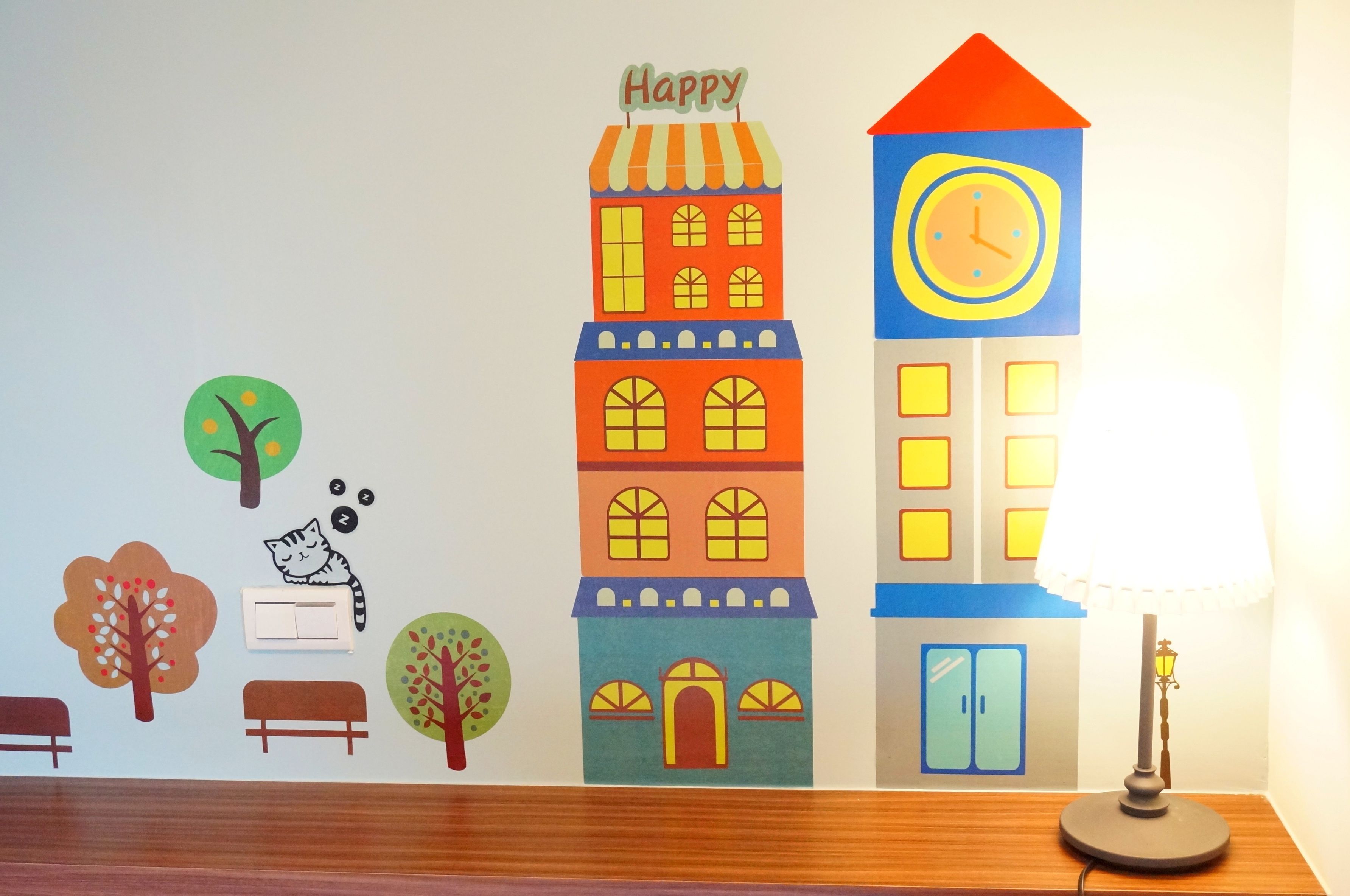 Un mural de un paisaje urbano colorido, con edificios, árboles y un gato.