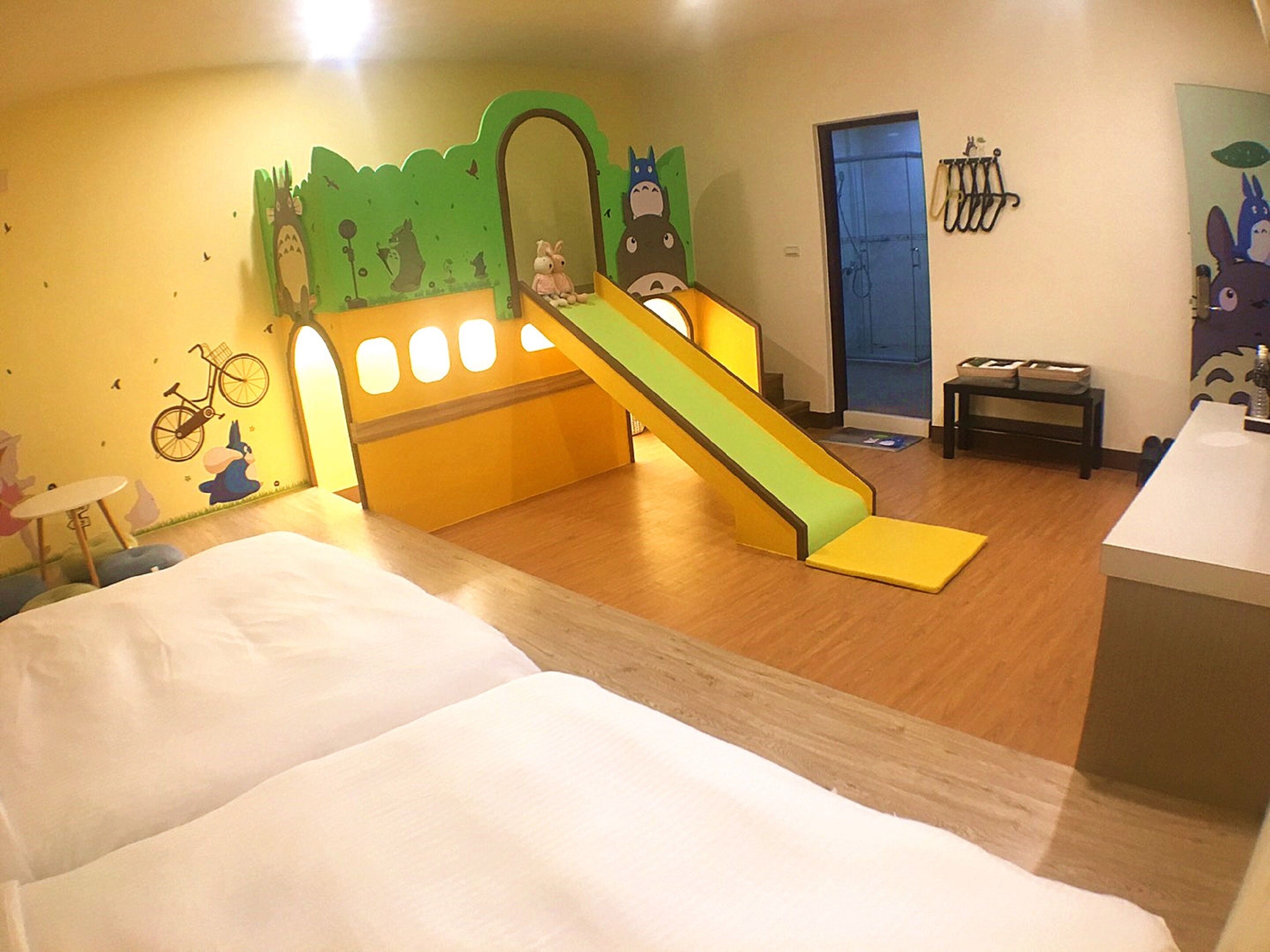 A children's play area with a slide, a mirror, and a bicycle decoration on the wall.