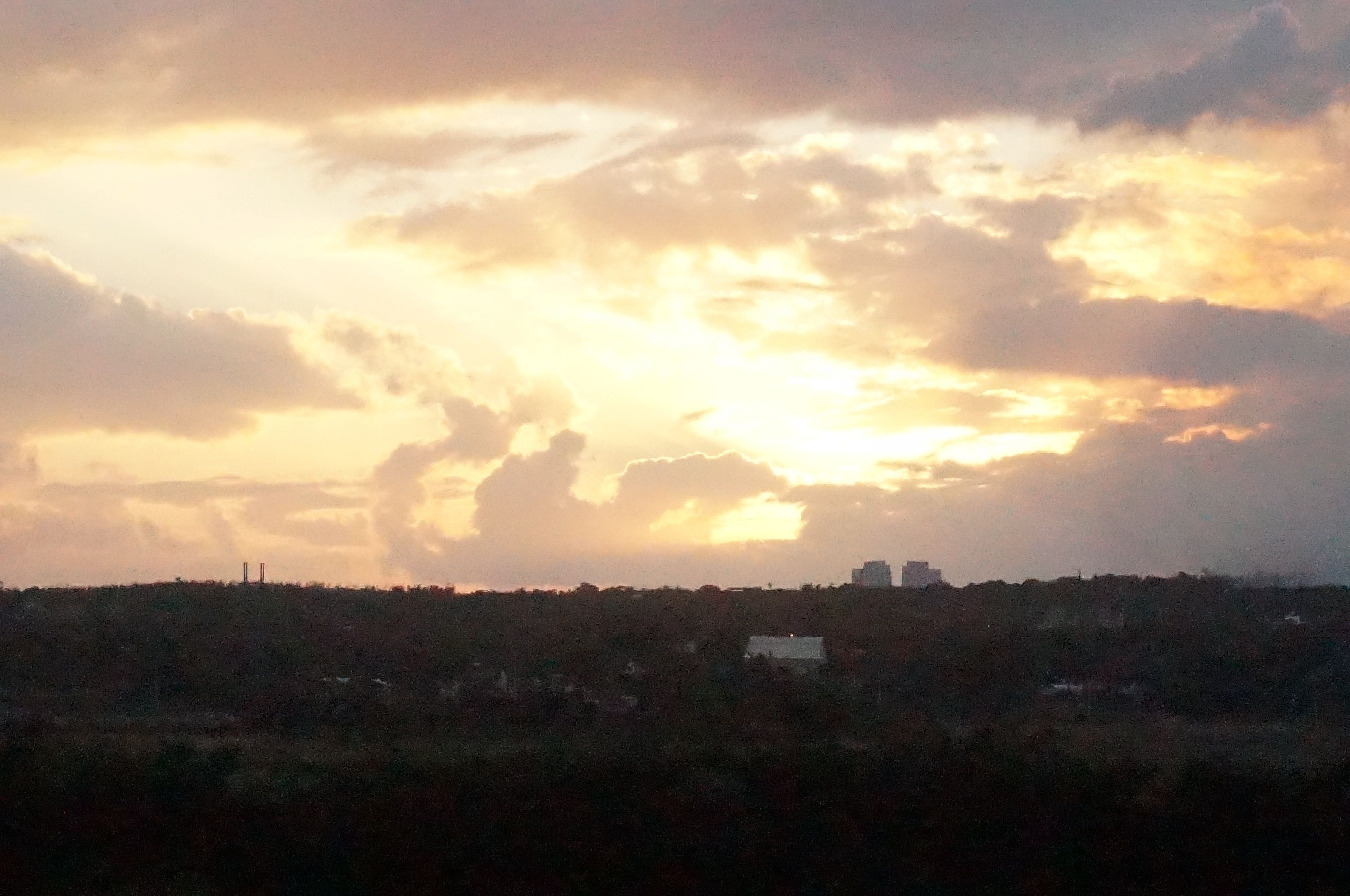 A sunset over a cityscape with buildings silhouetted against the sky.