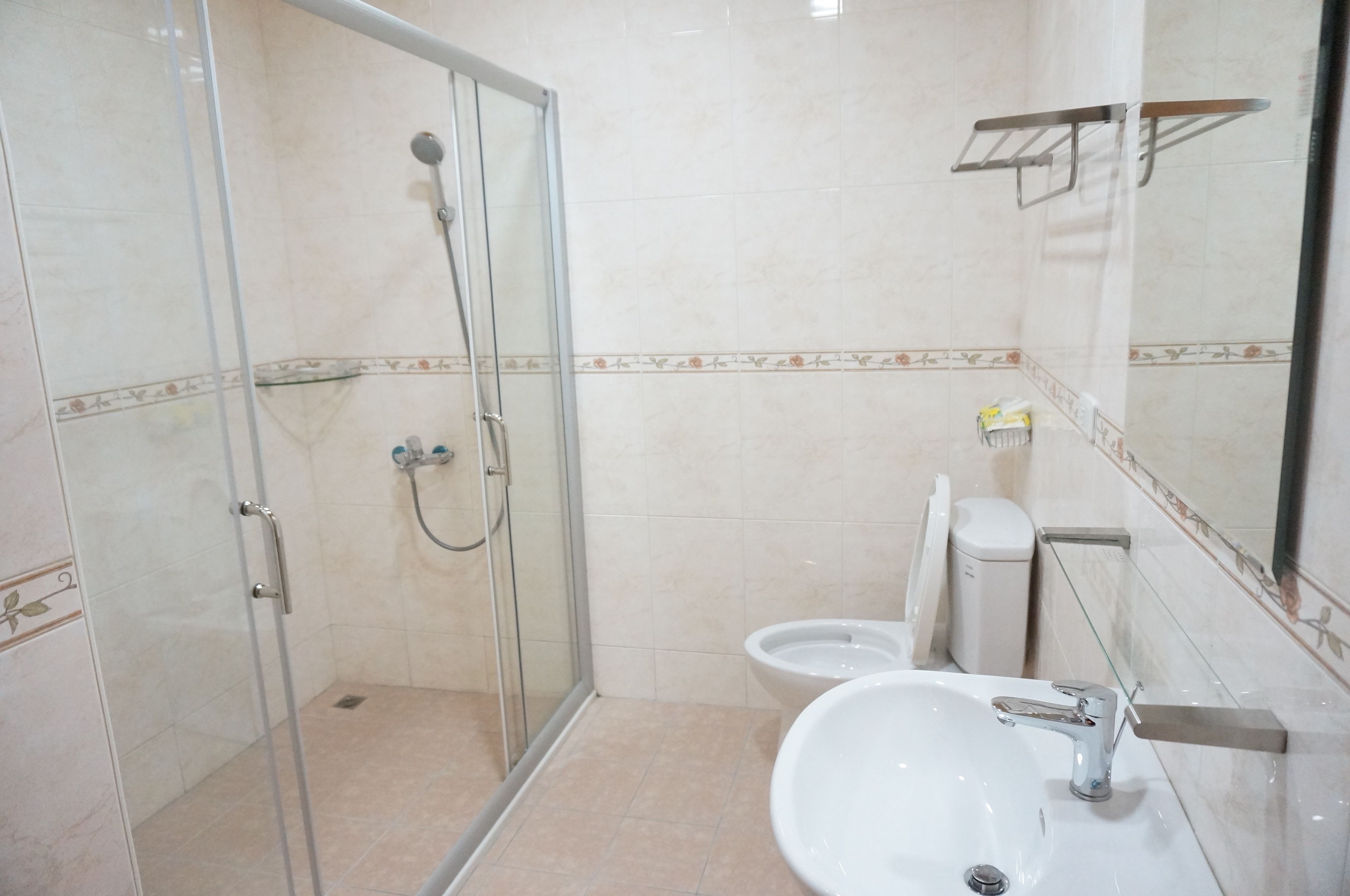 Une salle de bain avec une douche à parois de verre, un lavabo avec un miroir et des toilettes.