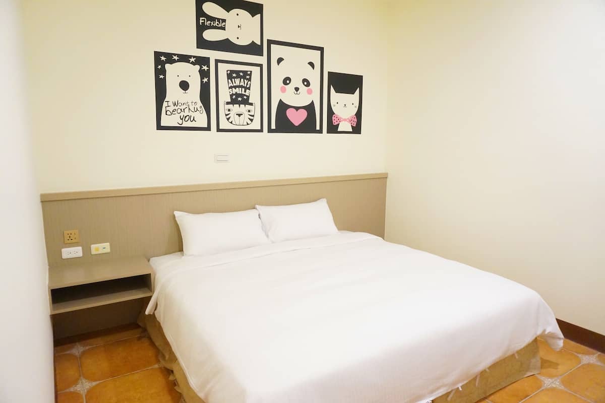A neatly made bed with white linens in a hotel room.
