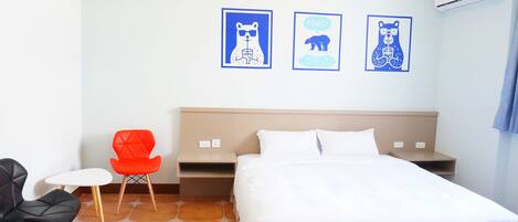 Une chambre d’hôtel comprenant un lit, une petite table, deux chaises et trois œuvres d’art murales.