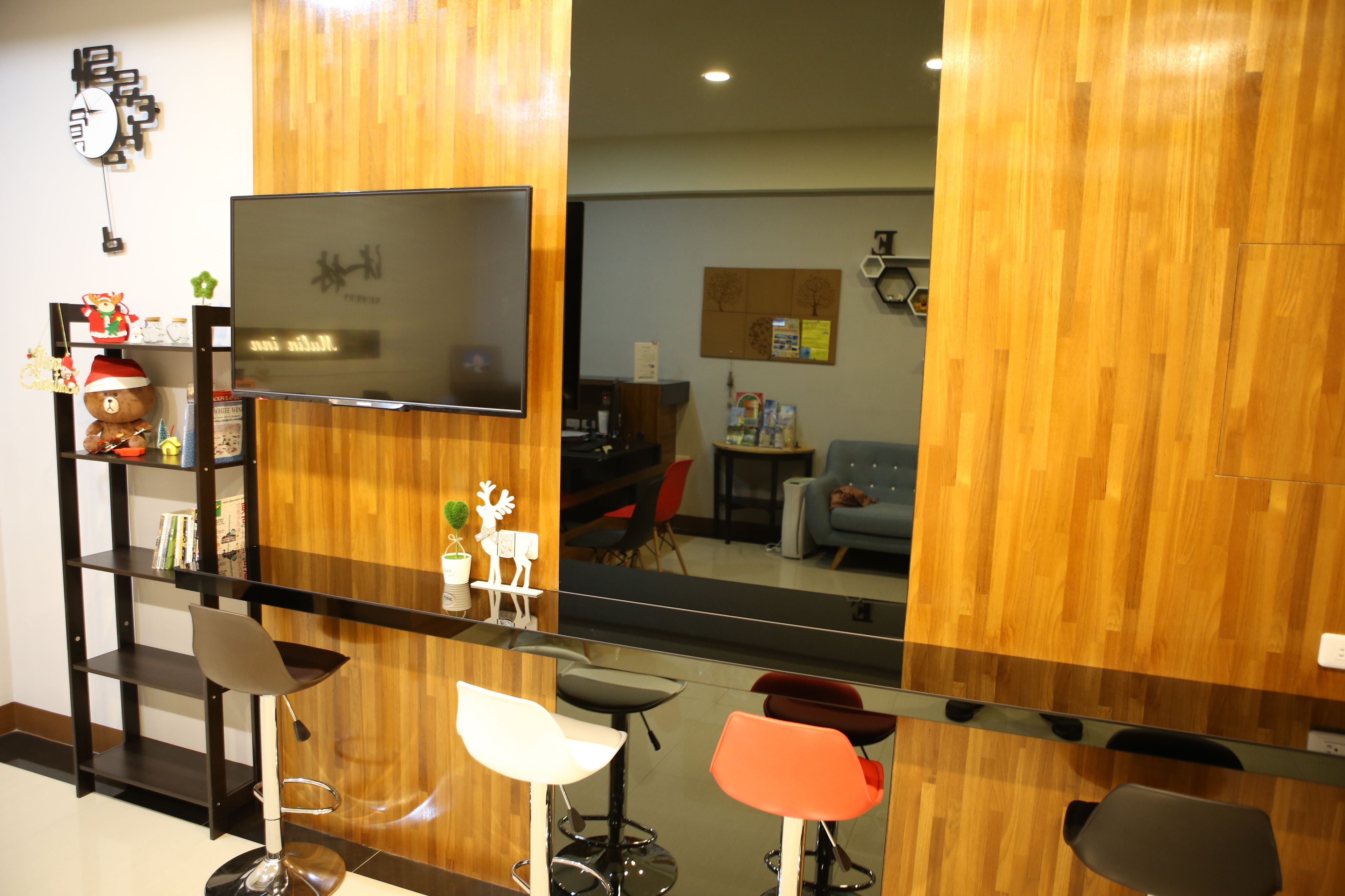 A modern room with a wooden partition, a flat-screen TV, and a bar area with stools.
