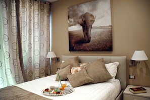 A hotel room with a bed, pillows, a tray with breakfast, a lamp, and a painting of an elephant. - Gregori Guest House (Rome)