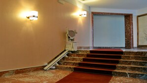 A staircase with marble steps and a red carpet, leading to a room with a white door and a framed picture on the wall. - Gregori Guest House (Rome)