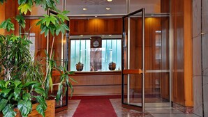 A lobby with wooden paneling, a red carpet, and potted plants. - Gregori Guest House (Rome)