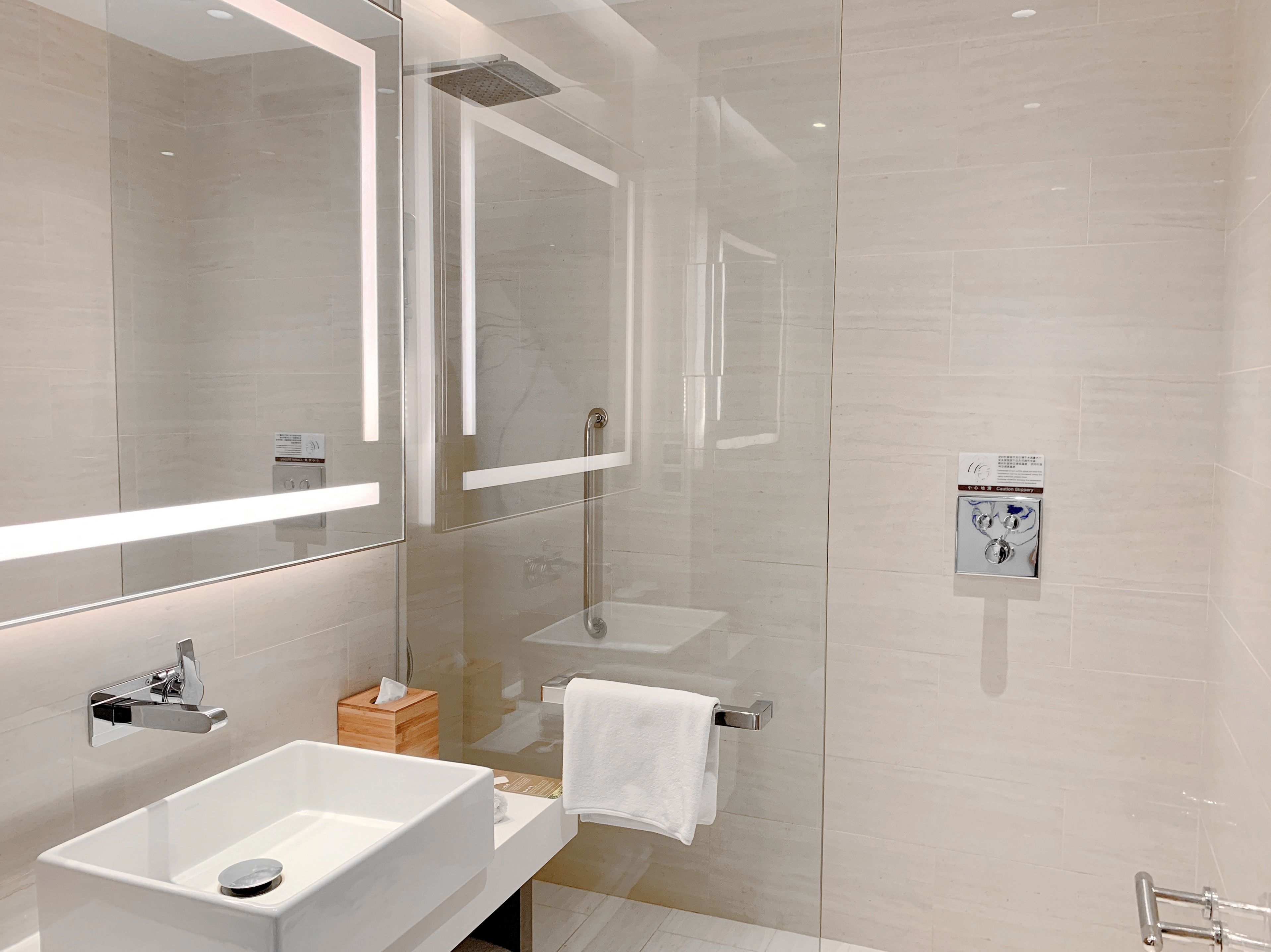 Un baño moderno con ducha de vidrio, un lavabo blanco y un espejo sobre él.
