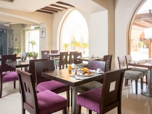 A dining area with tables and chairs, a window with a view, and a door leading outside. - El Jabal Sokhna Hotel (Ataqah)