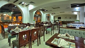 Un restaurante con varias zonas de comedor, incluyendo cabinas y mesas, con una decoración interior moderna y luz natural.