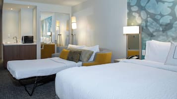 Habitación de hotel con dos camas, un escritorio con computadora, un espejo y una pared con diseño texturizado.