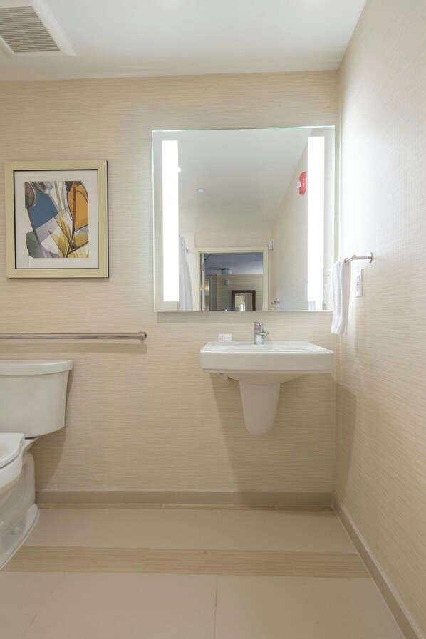 A bathroom with a toilet, sink, and mirror.
