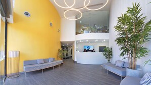 Un hall d’entrée moderne avec un comptoir d’accueil incurvé, des espaces de détente et une grande plante.
