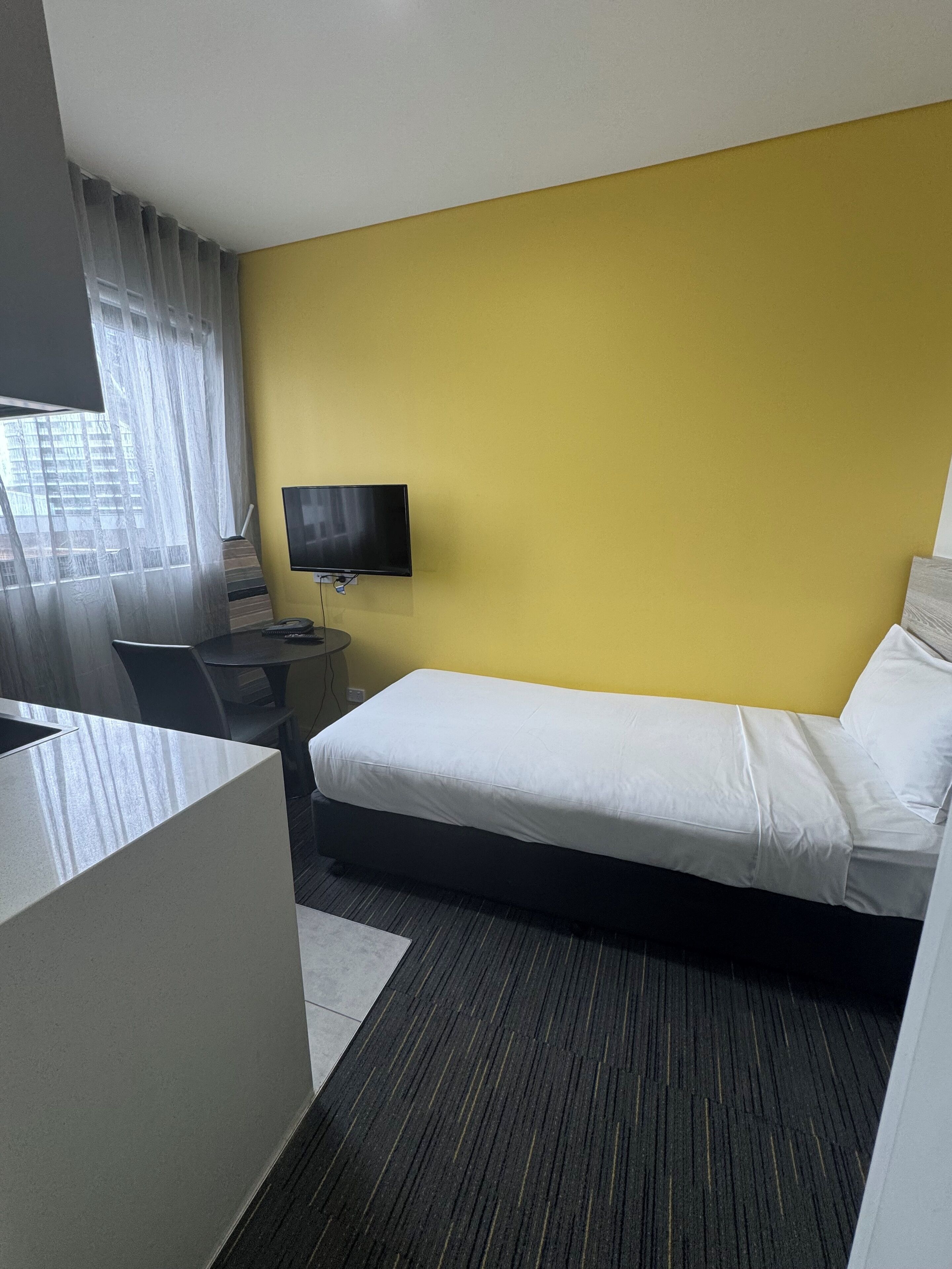 Ein Hotelzimmer mit Bett, Fernseher, Schreibtisch und Stuhl.