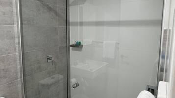 Ein modernes Badezimmer mit einer Duschkabine, einer Toilette und einem Waschbecken mit Handtuchhalter.
