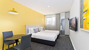 Une chambre d’hôtel avec deux lits, une table à manger et un téléviseur.