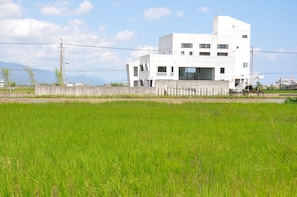 A modern white building with a flat roof, large windows, and a concrete wall in front.