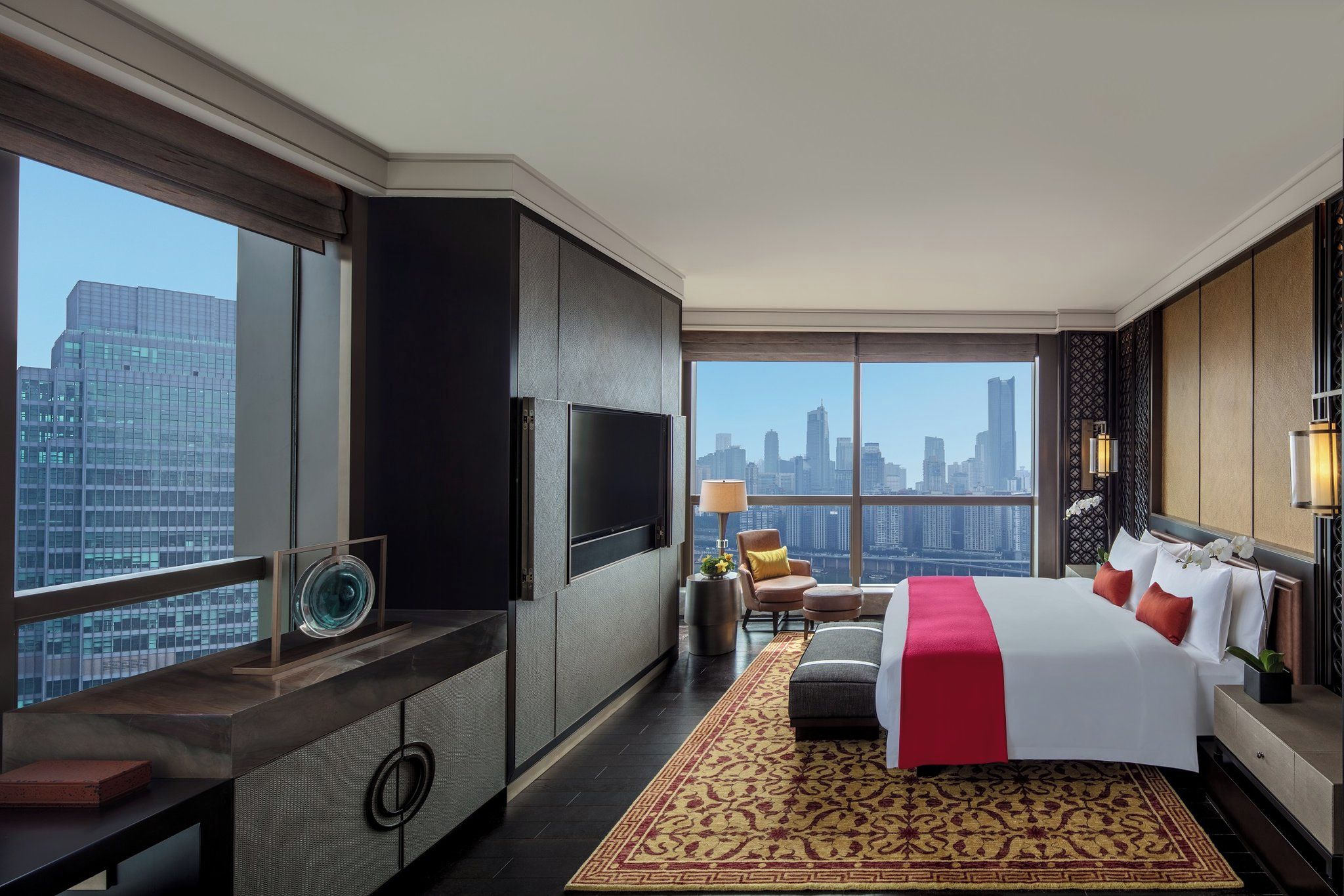 A hotel room with a large bed, a TV, a city view, and a modern design.