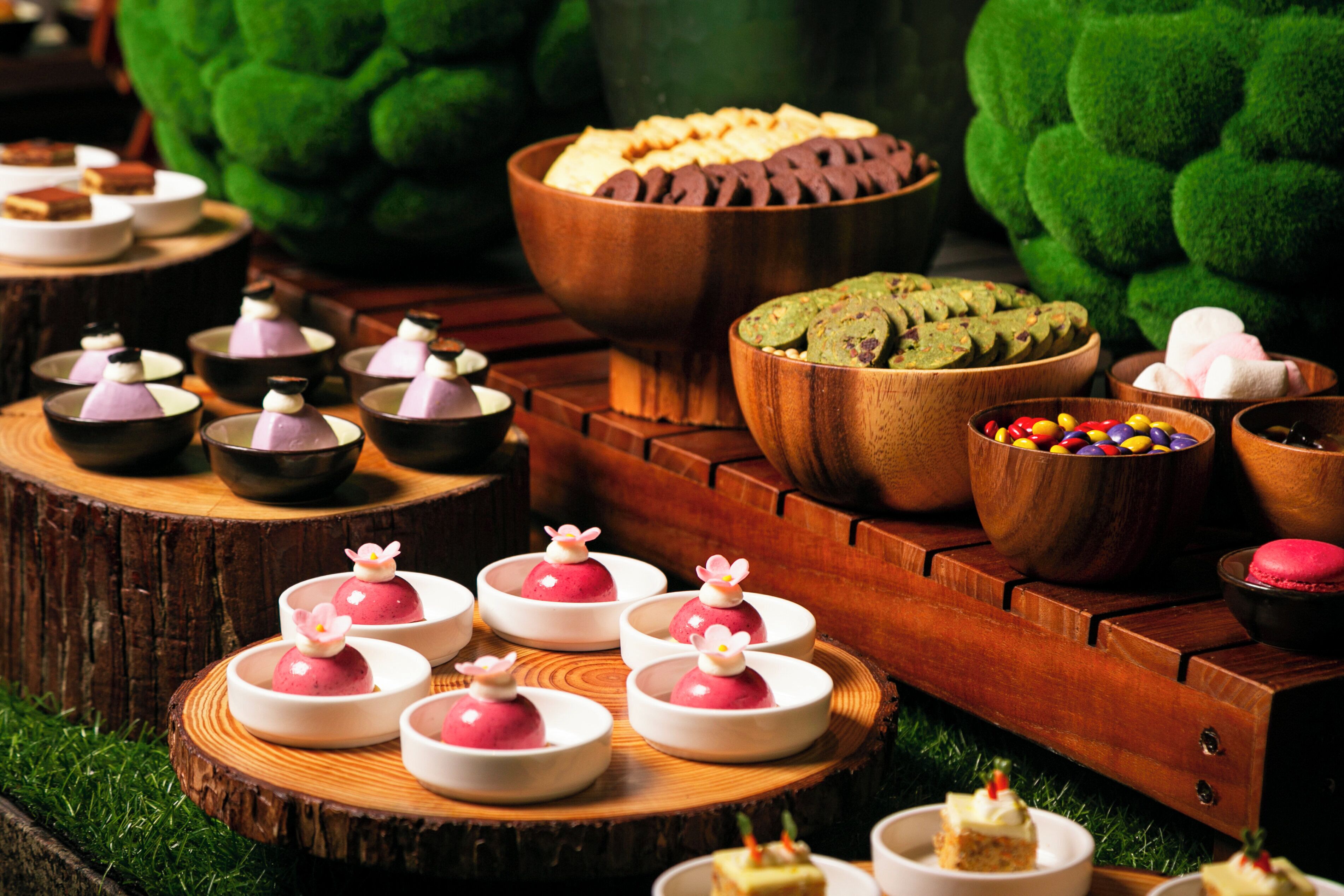 A variety of desserts and snacks arranged on wooden tables and platters.