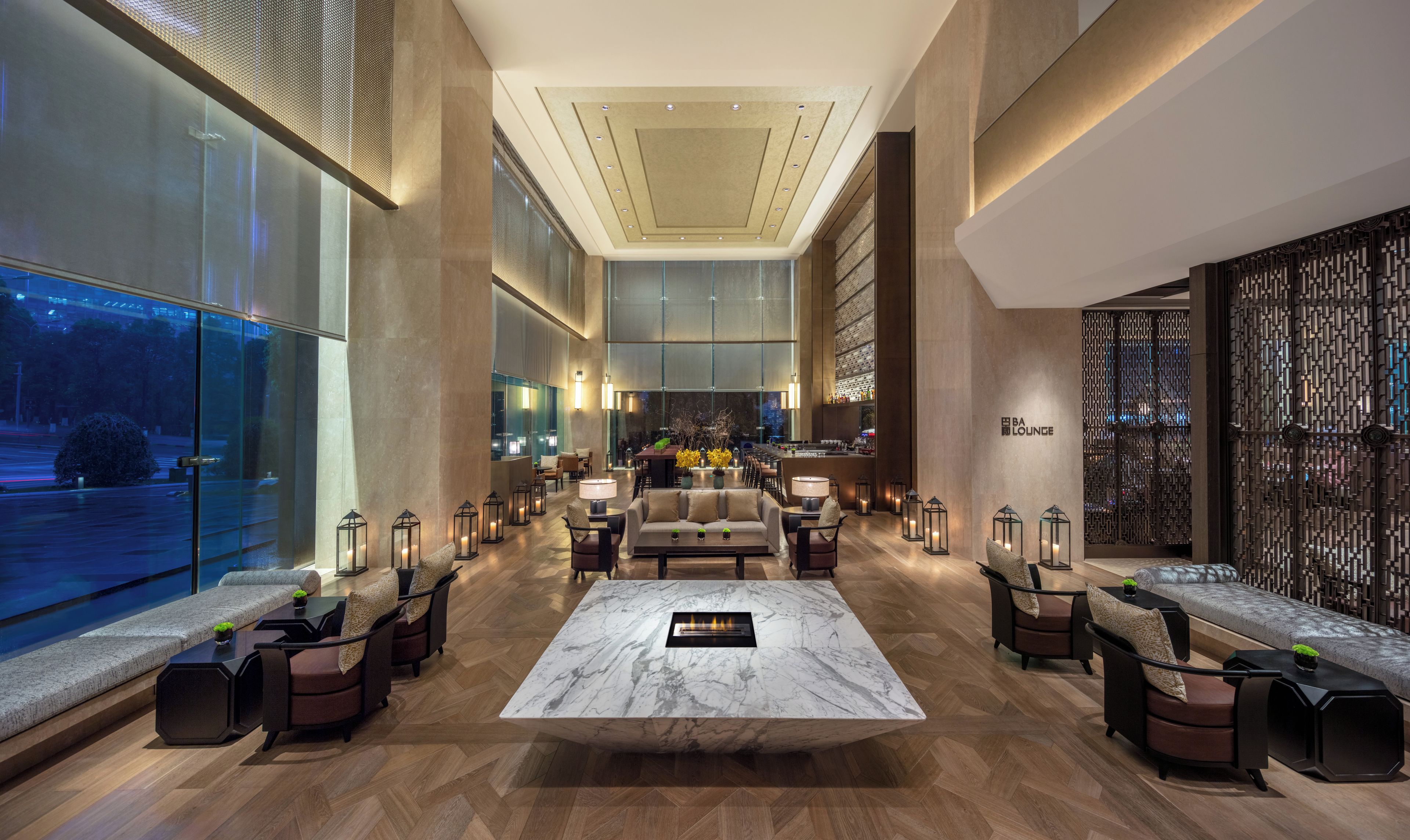 A spacious lobby with a central seating area, a bar, and a view of the outdoors.