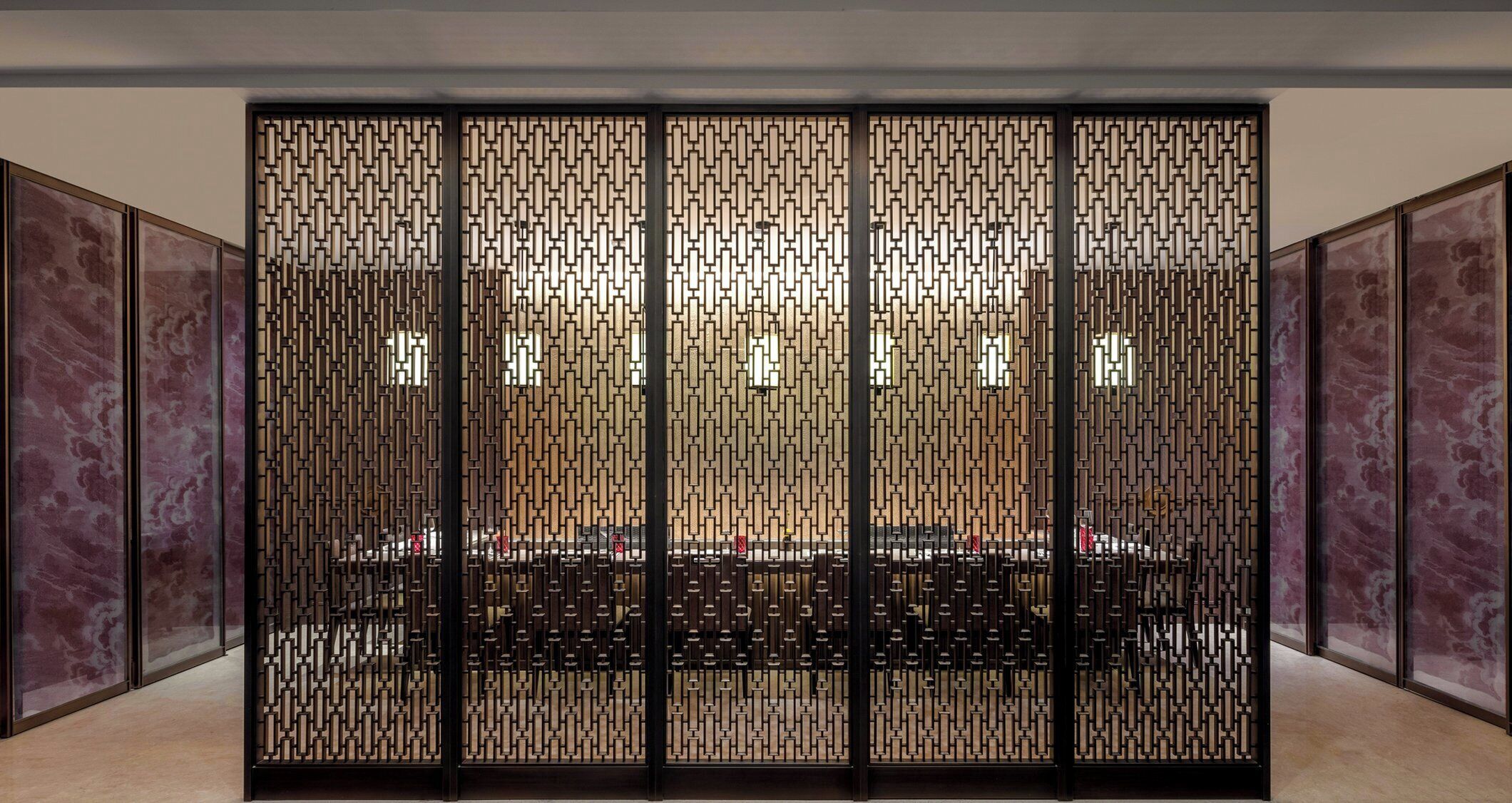 A conference room with a long table, a decorative screen, and marble walls.