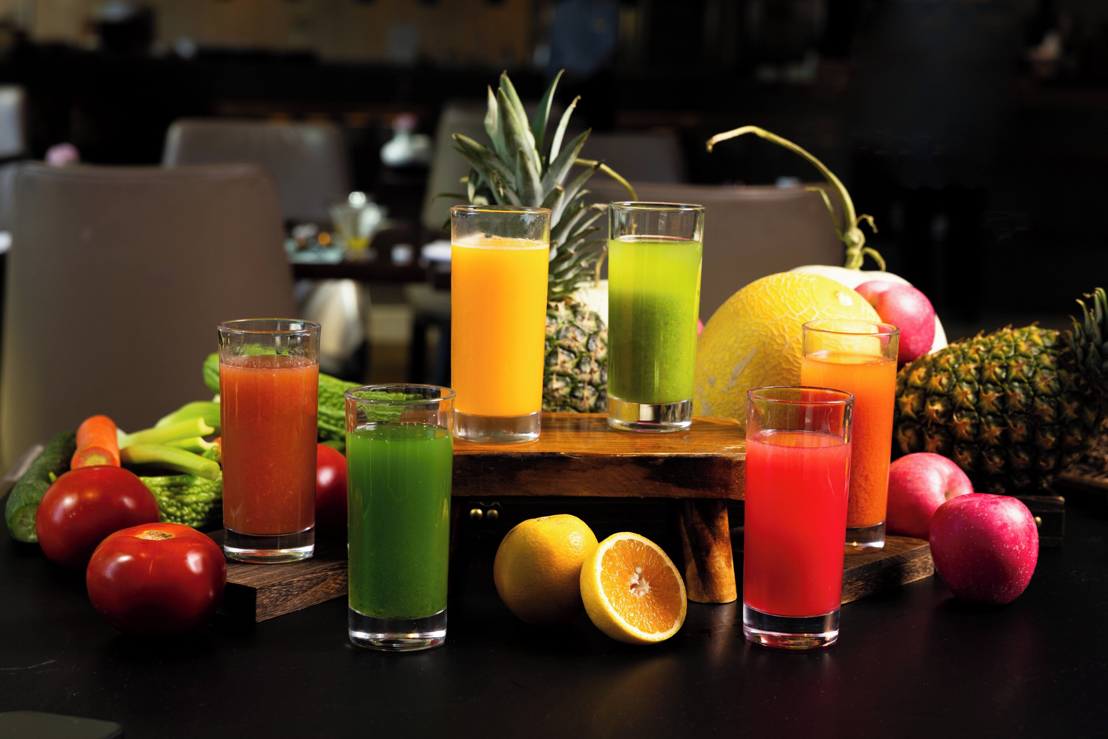 A table with various fruits and drinks, including a pineapple, oranges, and glasses of juice.