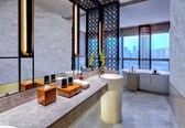 A modern bathroom with a large mirror, two sinks, a bathtub, and a city view.