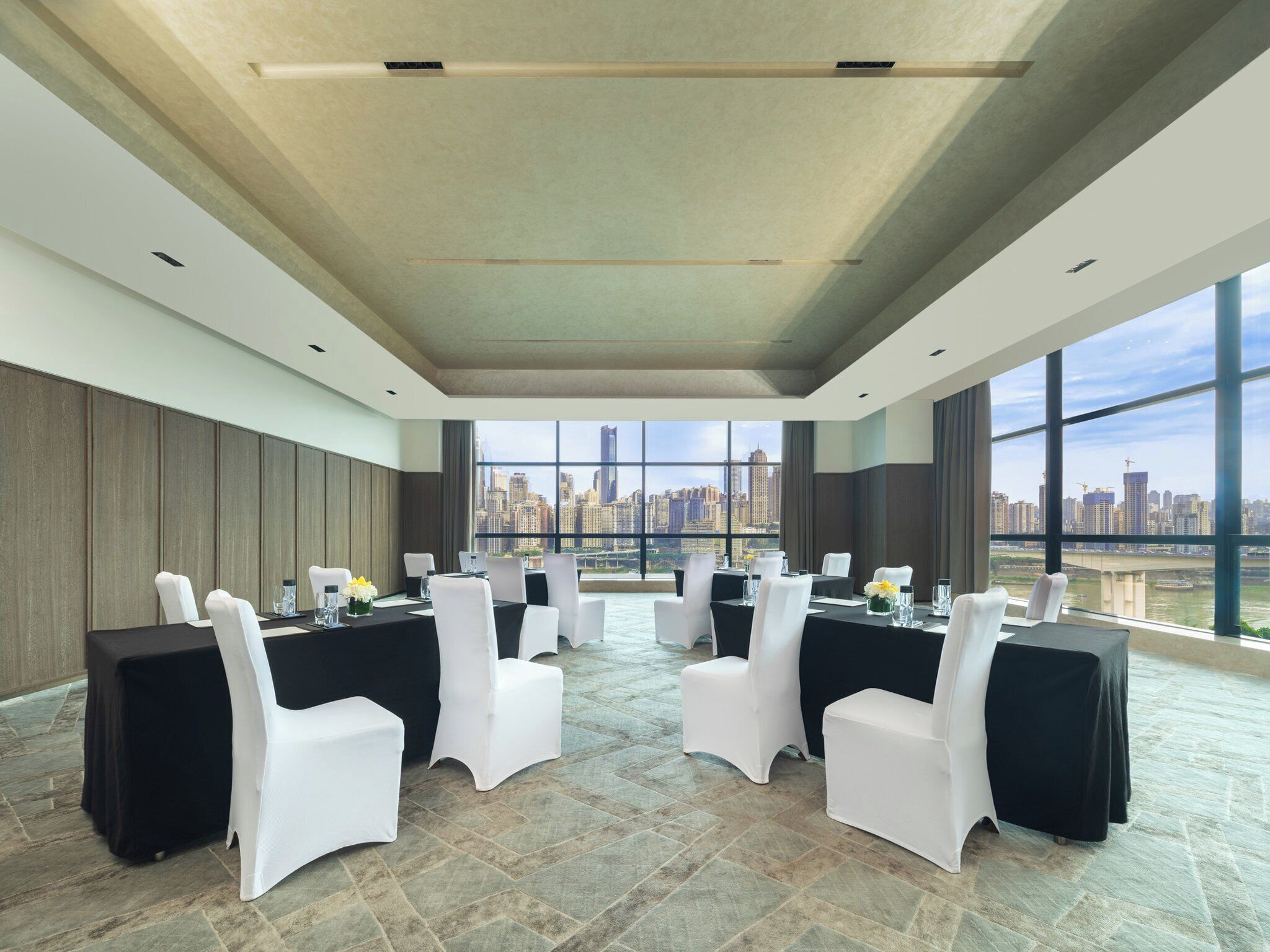 Un salón de conferencias con vistas a la ciudad, amplias ventanas y un diseño de techo moderno.