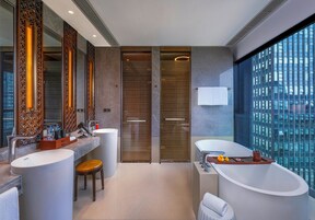 Un baño moderno con dos lavamanos, una bañera y un amplio ventanal con vistas a la ciudad.