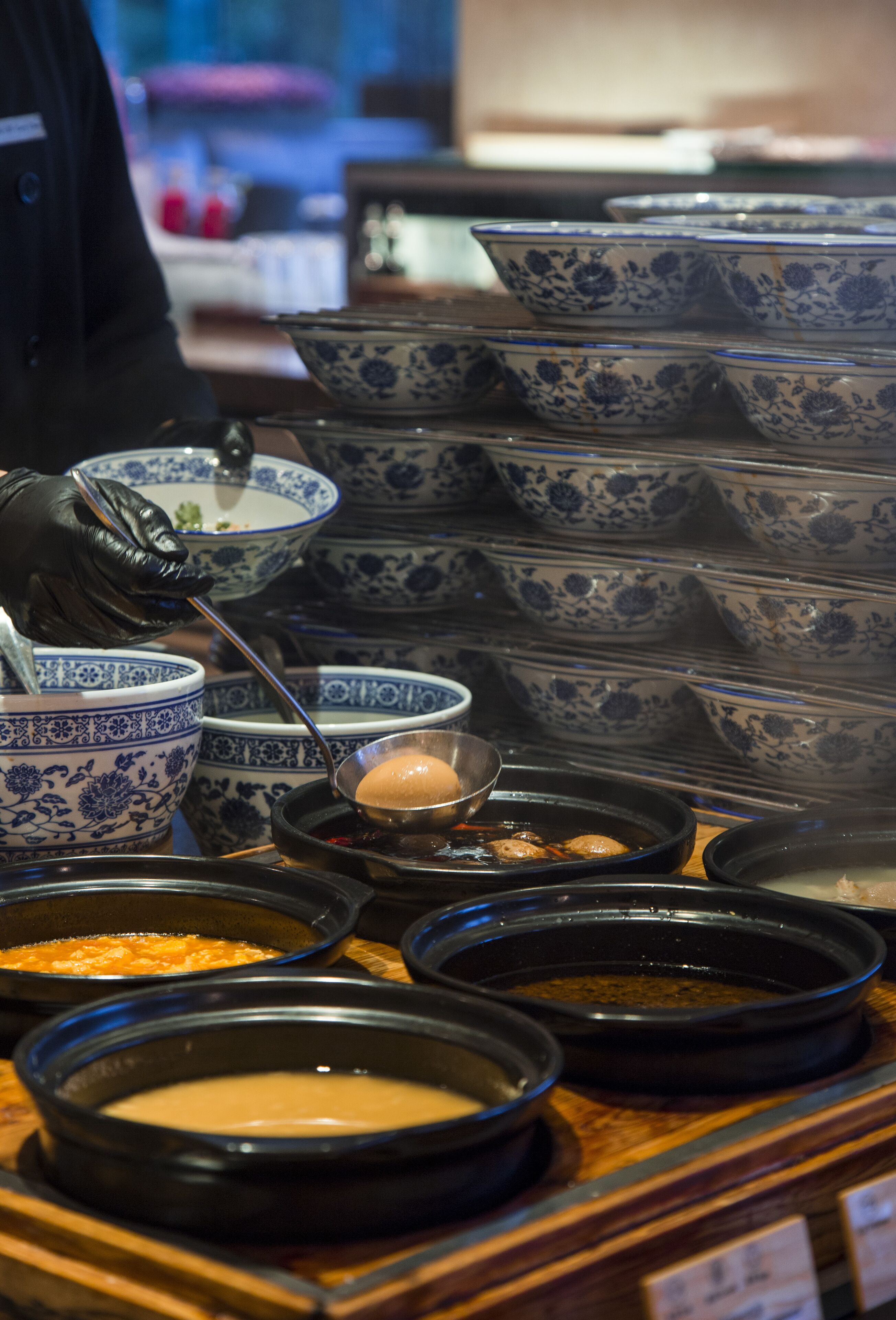 A buffet with various dishes in bowls and black plates, arranged on a wooden table.