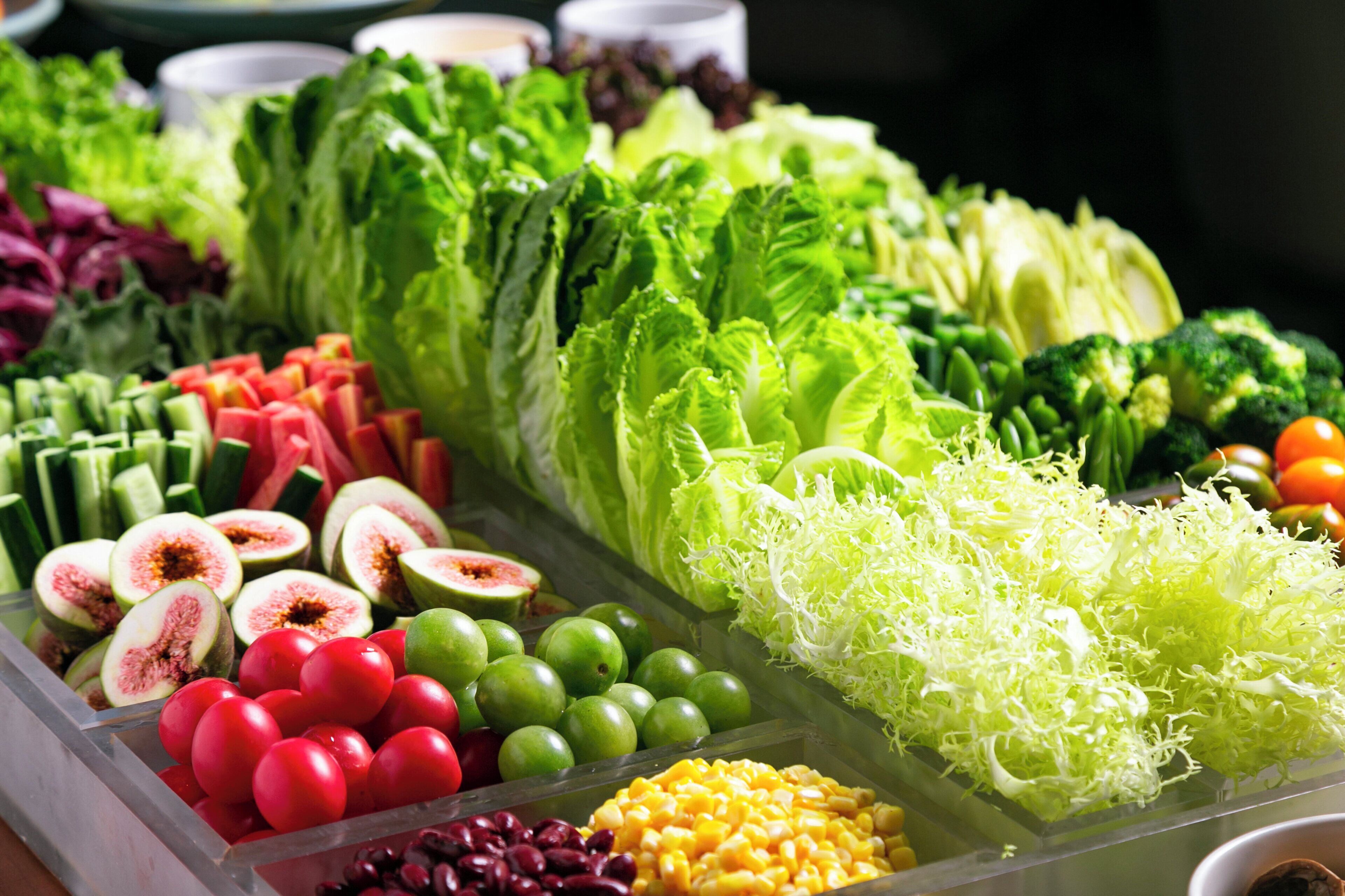 A variety of fresh vegetables and fruits displayed in a clear container.
