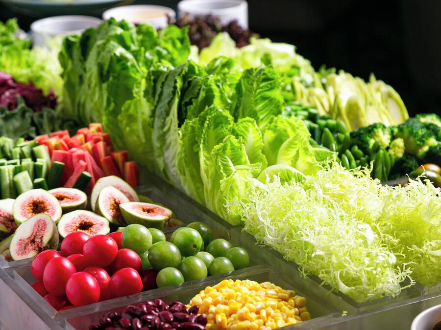A variety of fresh vegetables and fruits displayed in a clear container.