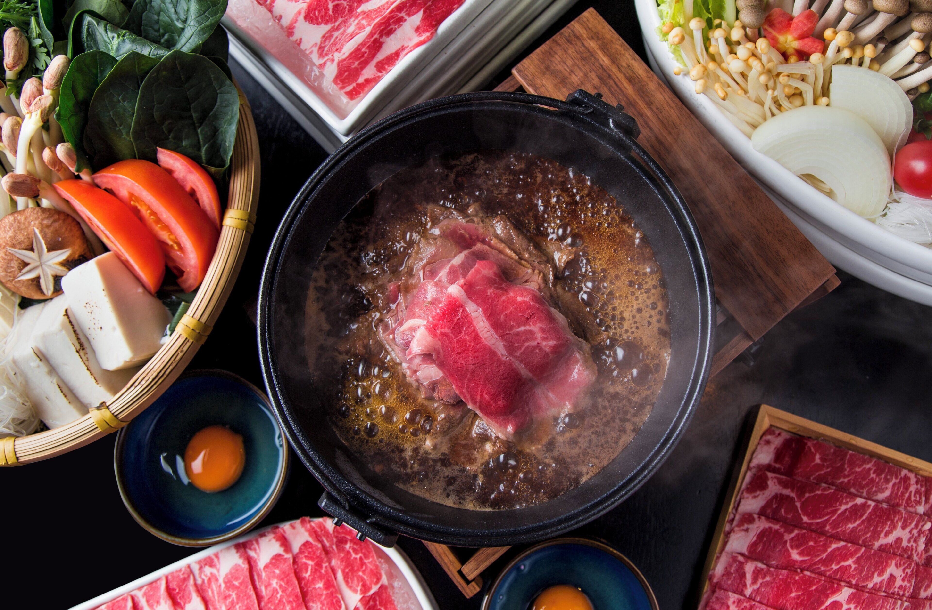 Una olla caliente con carne, verduras y hongos.