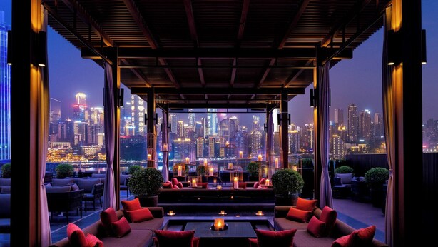 Un salón en la azotea con vistas al horizonte de la ciudad, amueblado con sofás y mesas, y velas.