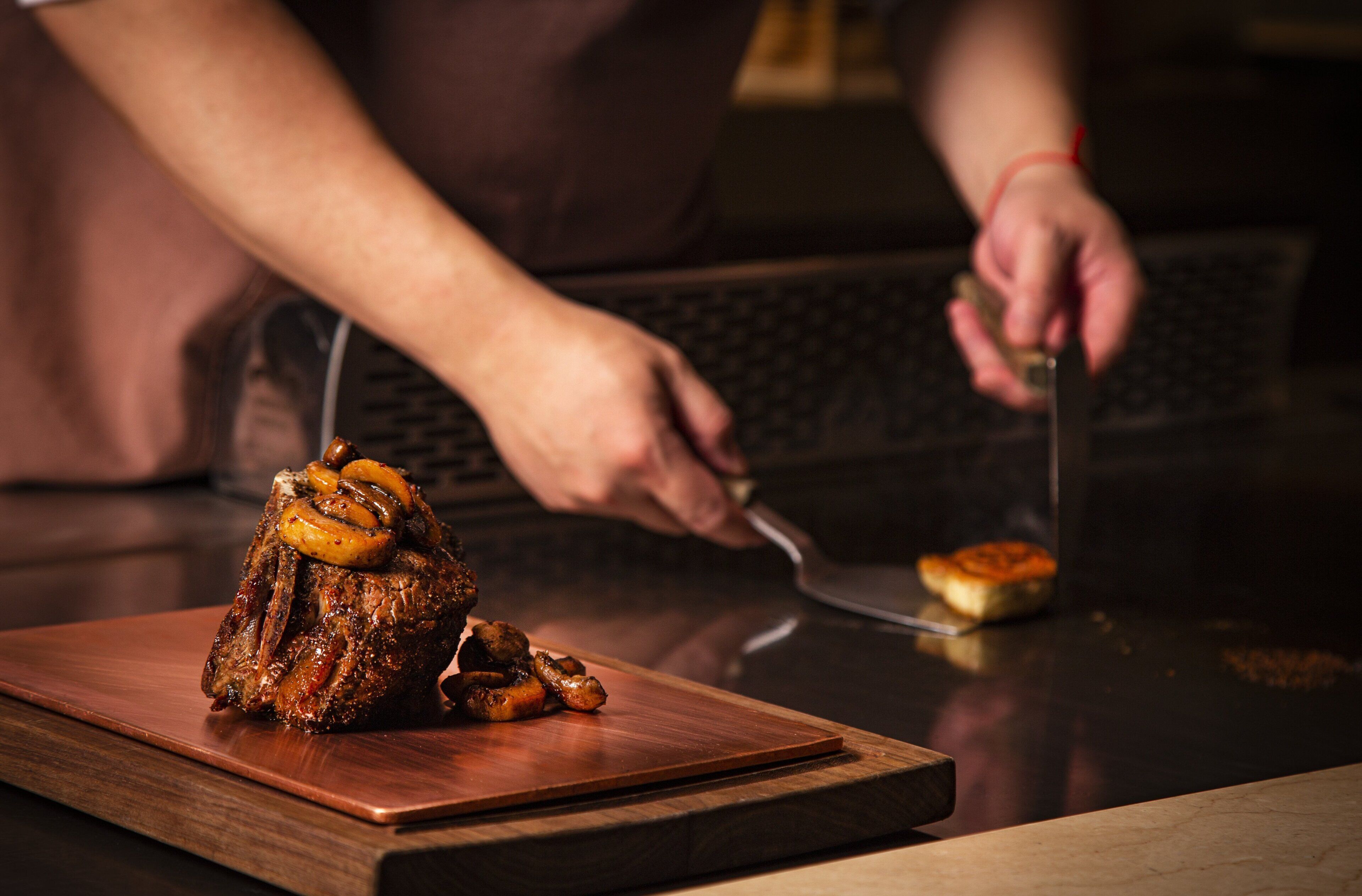 A person carving a large, roasted meat on a wooden cutting board.
