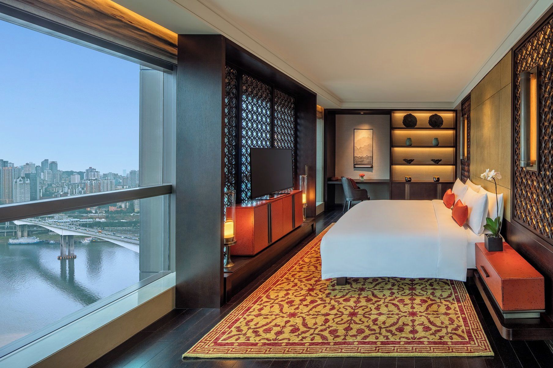 Een moderne hotelkamer met een groot bed, een bureau en uitzicht op een stadsgezicht.