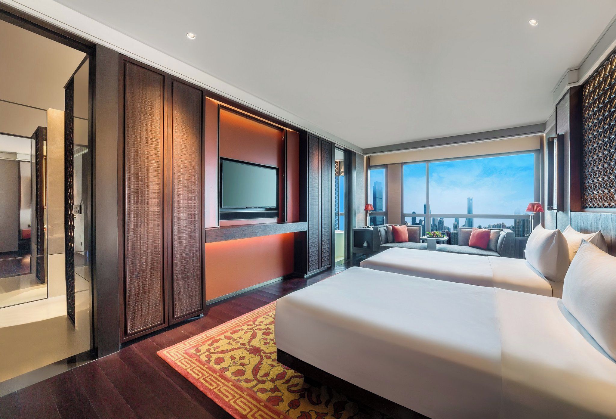 Una habitación de hotel moderna con una cama grande, televisor y vistas a la ciudad.