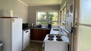 Una cocina compacta con refrigerador, microondas, estufa y pileta.
