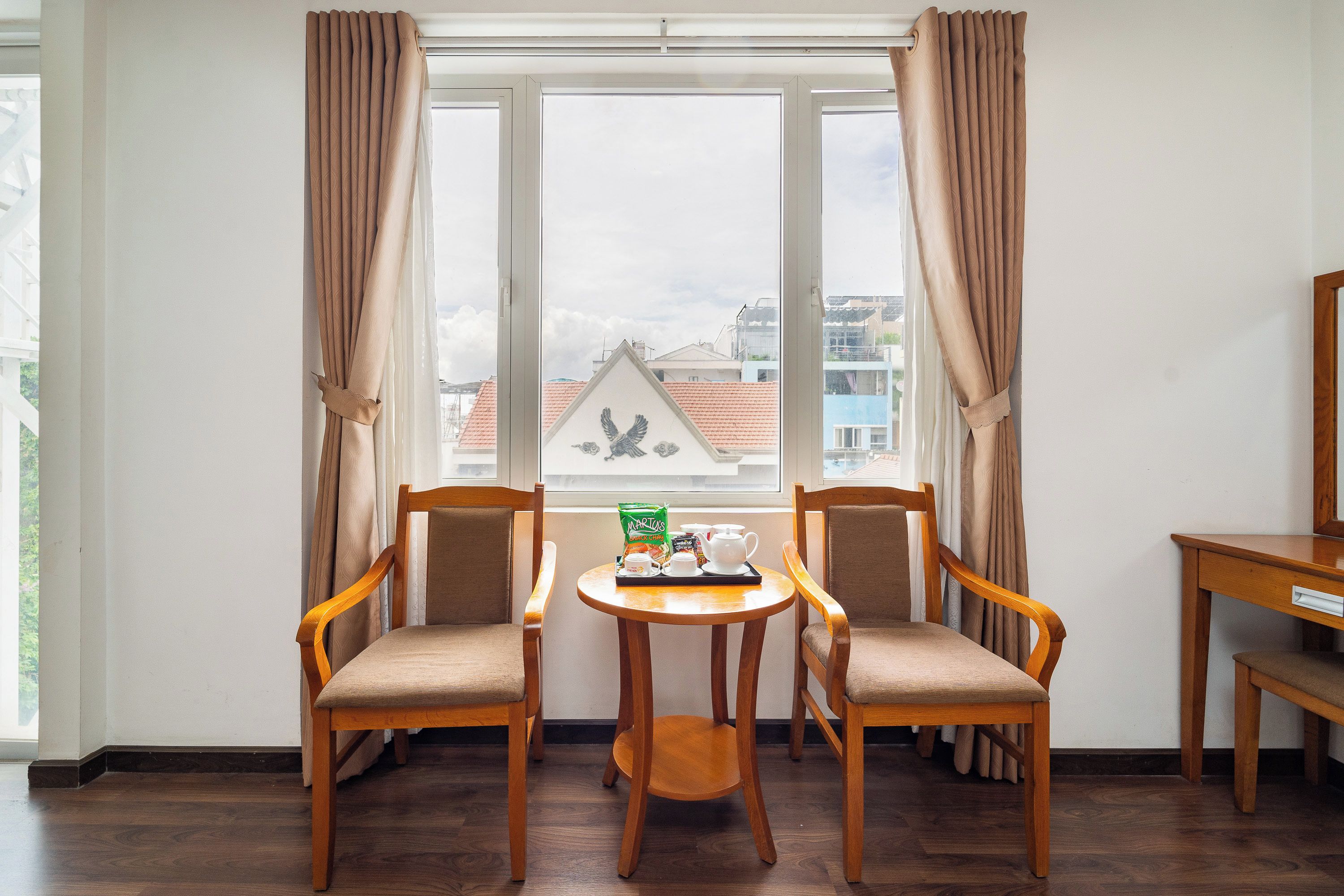 A room with two wooden chairs, a small round table, and a window with curtains.