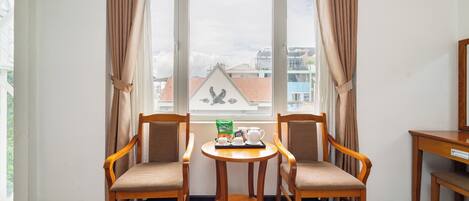 A room with two wooden chairs, a small round table, and a window with curtains.