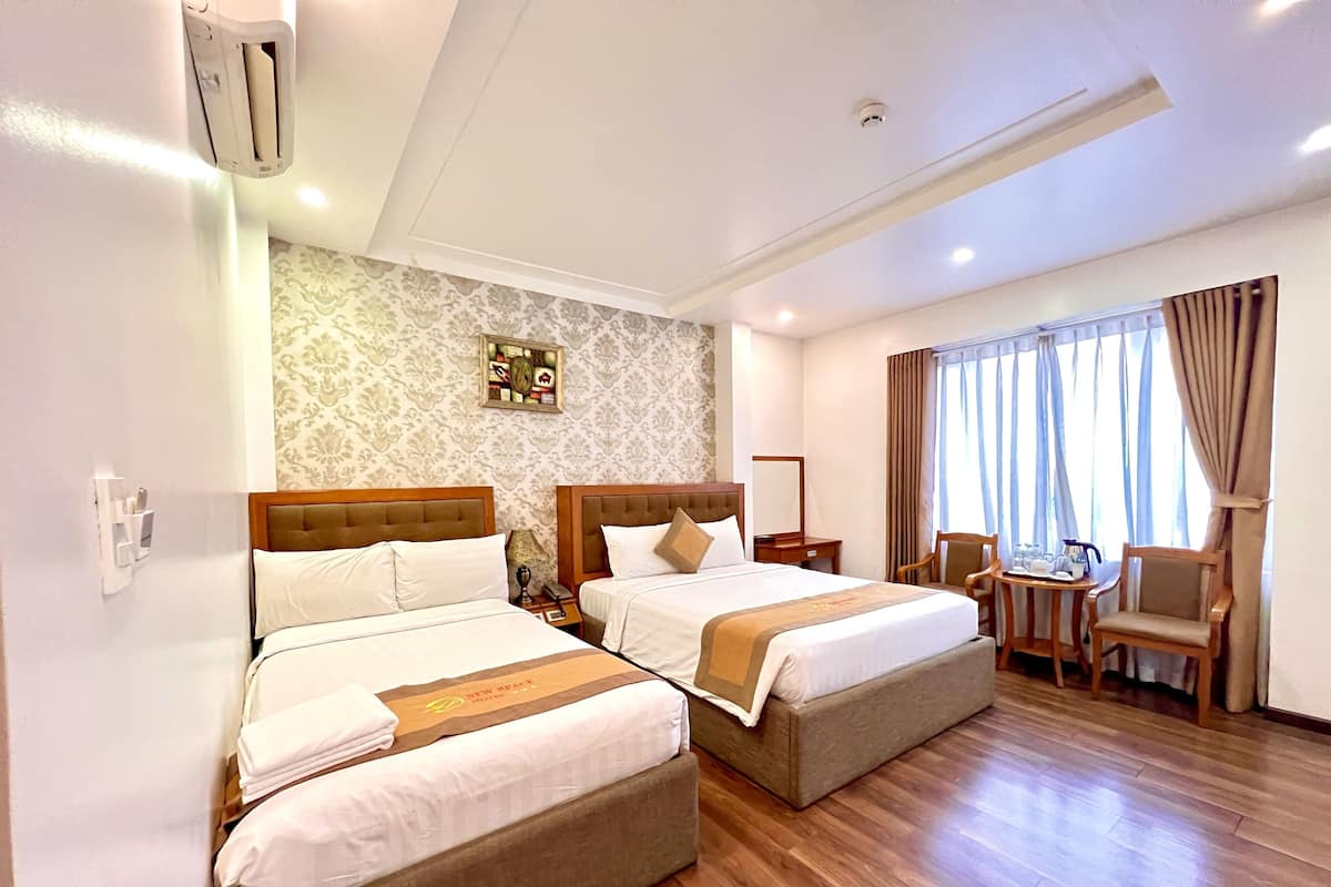 Une chambre d’hôtel avec deux lits, un bureau, des chaises et une fenêtre avec des rideaux.