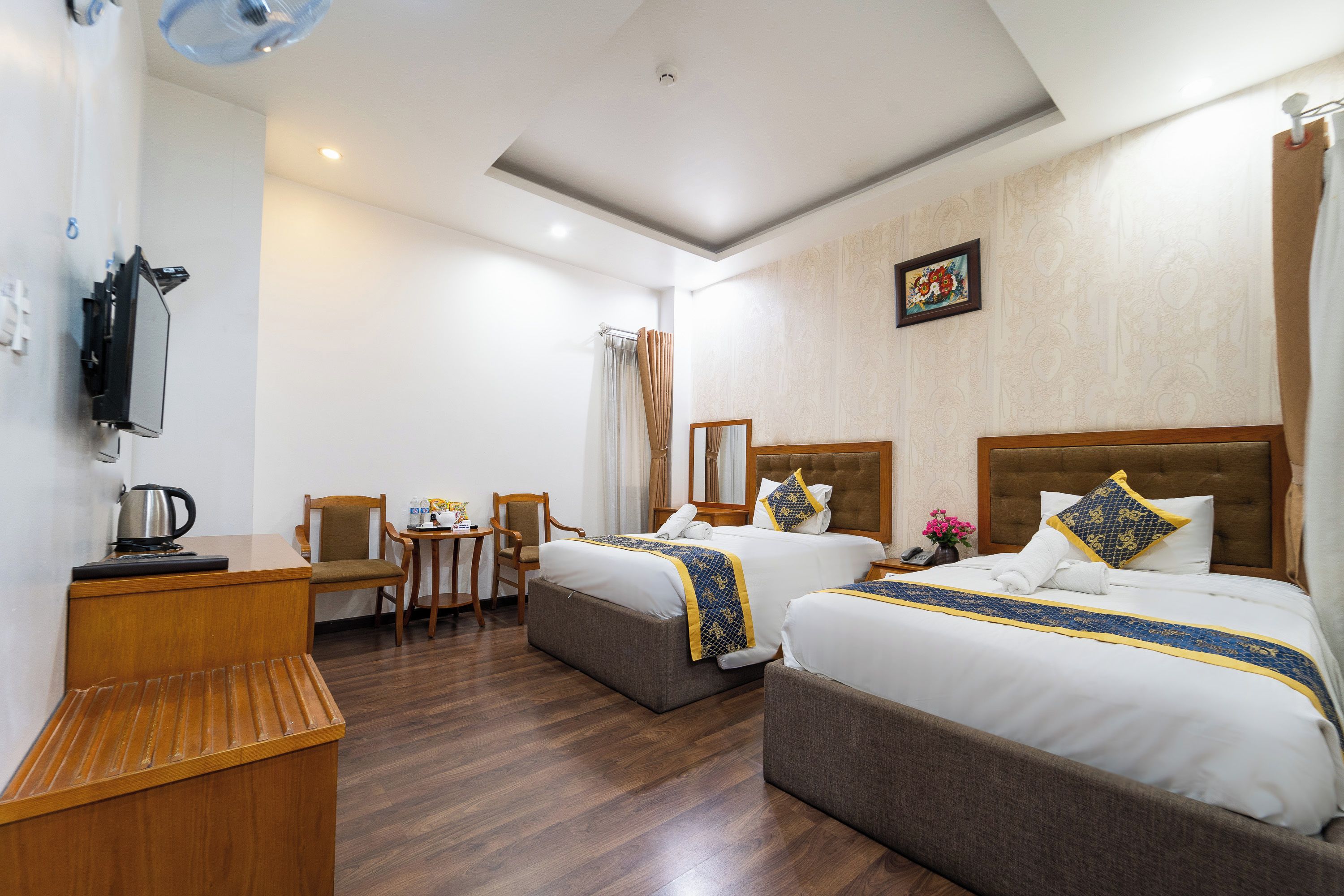 Une chambre d’hôtel avec deux lits, un bureau, une chaise, une petite table et un miroir.