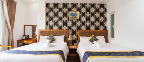 A hotel room with two beds, a nightstand, a lamp, and a picture on the wall.