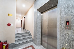 An elevator with a digital display, a push button, and a fire extinguisher on the wall. - New Angel Airport Hotel (Ho Chi Minh City)
