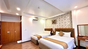 Hotelkamer met twee bedden, houten vloer, een garderobe, een airconditioningapparaat, een spiegel en een decoratief wandobject.