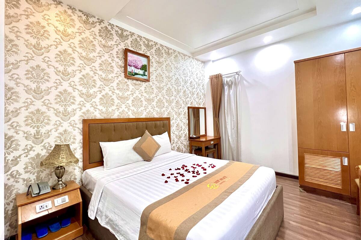 Une chambre d’hôtel comprenant un lit, une table de chevet, un miroir, une armoire et un mur décoratif.