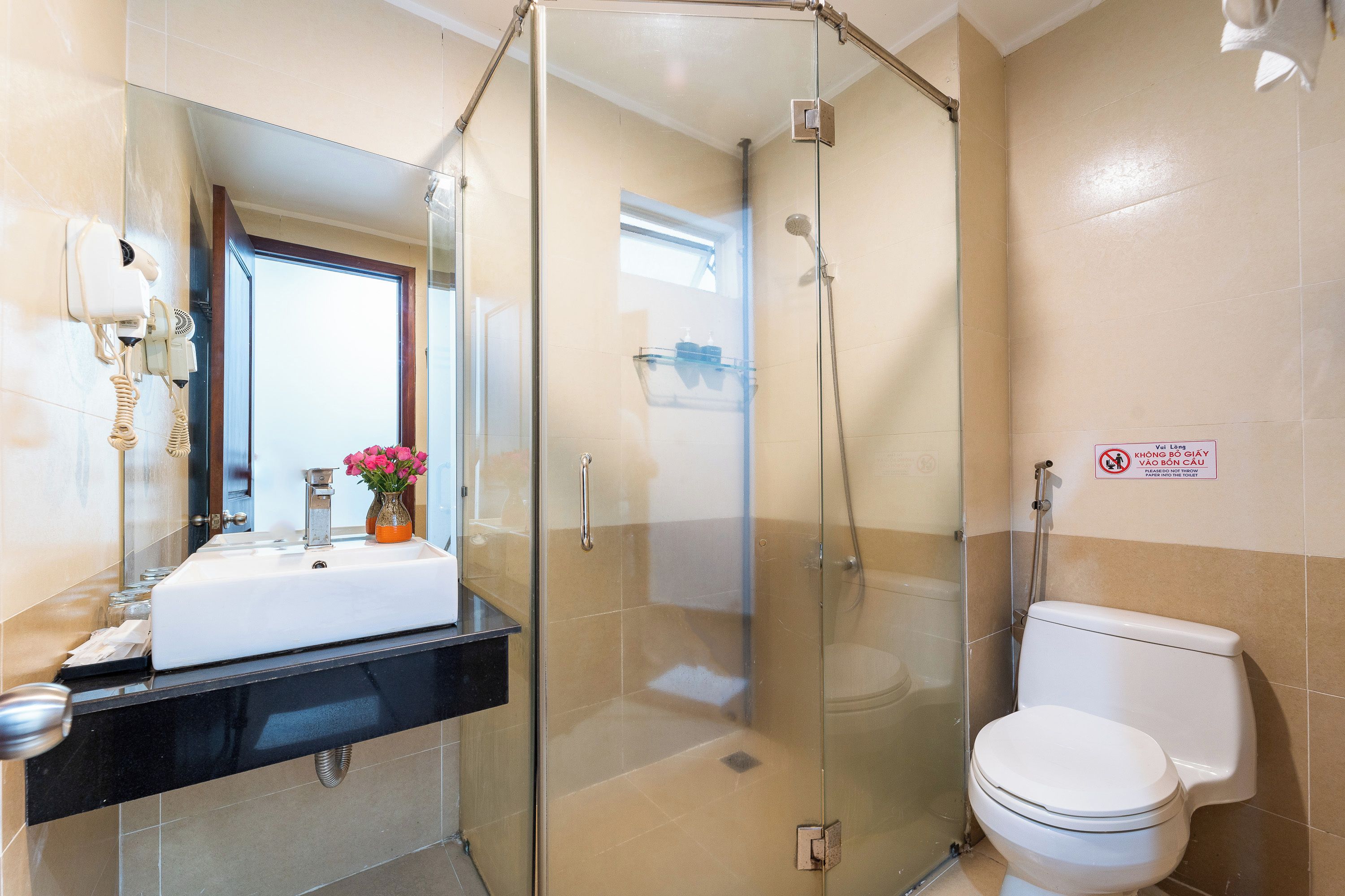 A bathroom with a glass-enclosed shower, a white toilet, and a sink with a mirror above it.